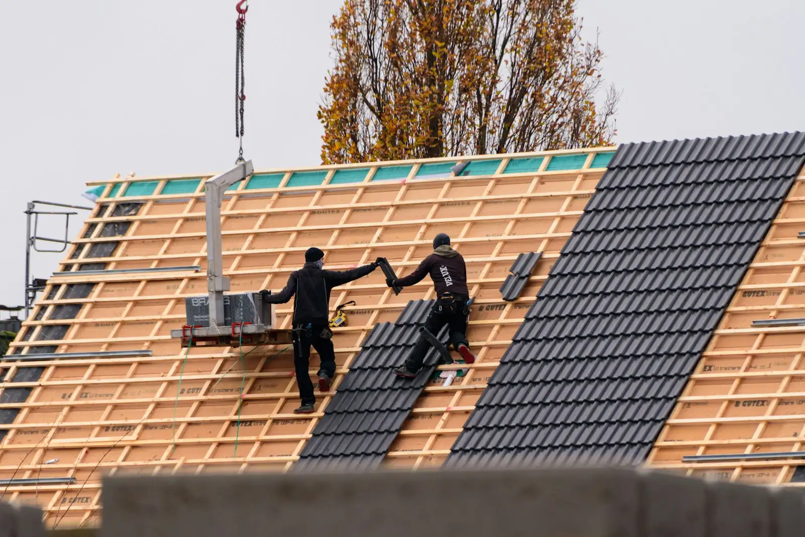 Pokrývači pokládají betonovou tašku na nový krov rodinného domu
